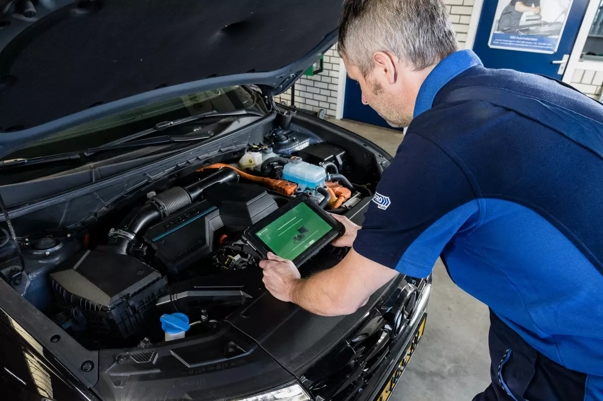 Monteur leest met een diagnoseapparaat een hybride auto uit in de werkplaats