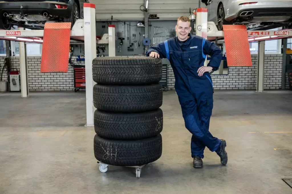 Een set banden op een rolwagen in de werkplaats, met de hefbruggen op de achtergrond