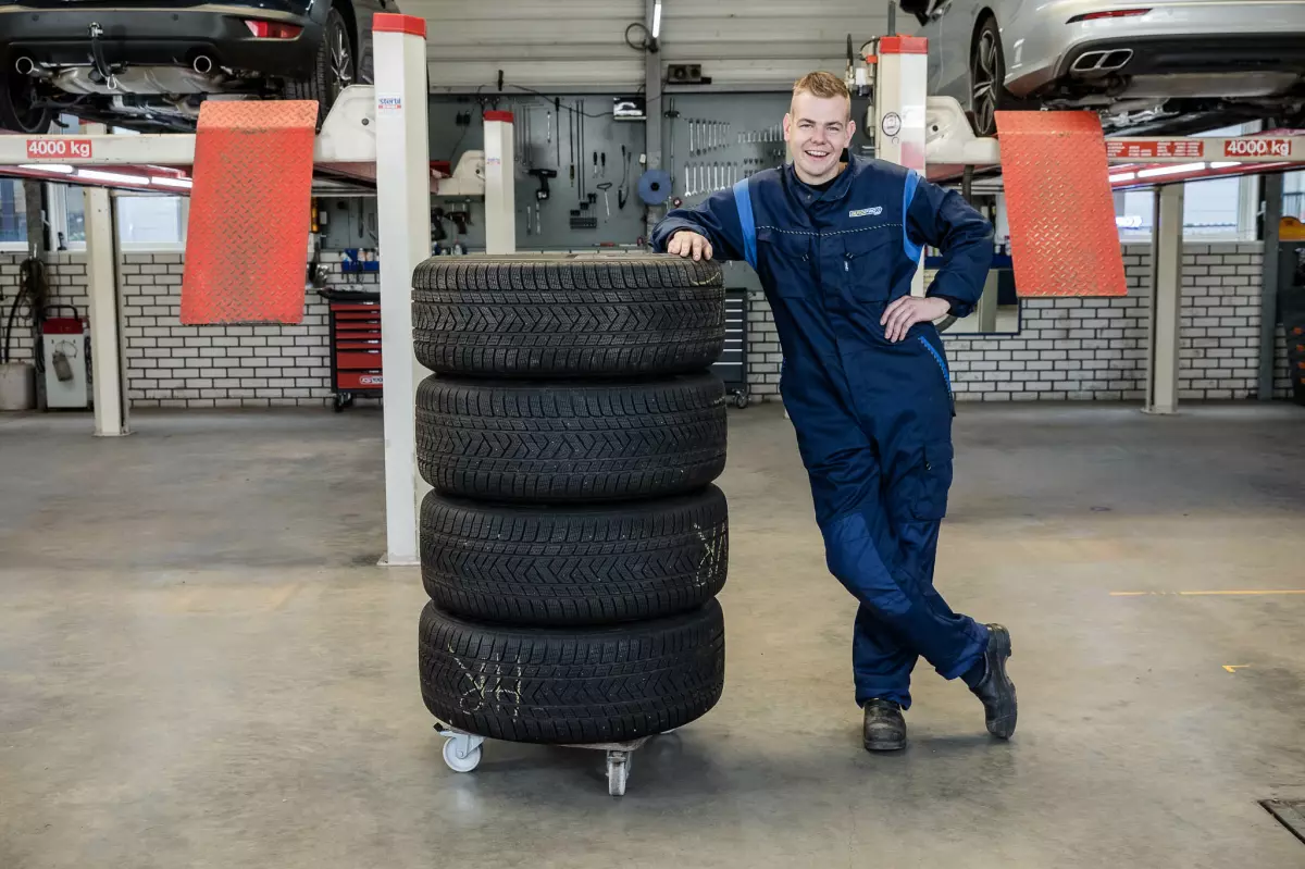 Een set banden op een rolwagen in de werkplaats, met de hefbruggen op de achtergrond